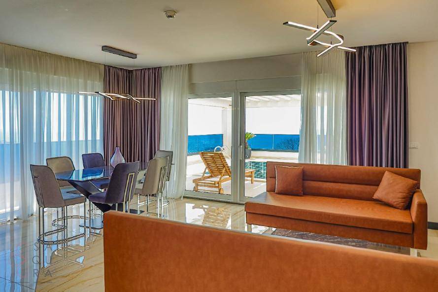 Heller Wohn- und Essbereich mit Zugang zur Terrasse und Blick auf den Poolbereich.