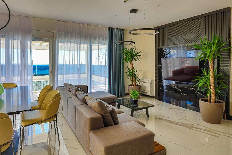 Eleganter Wohnbereich mit bequemer Couch, dekorativen Pflanzen und weitem Blick auf das Meer.