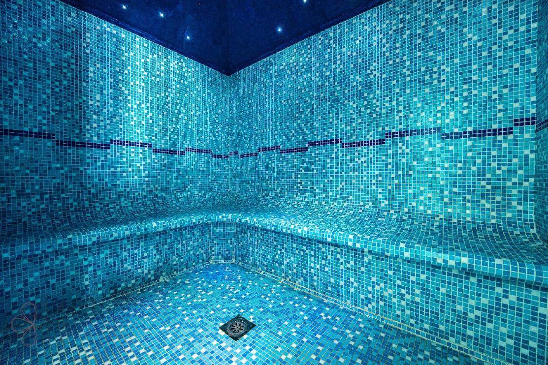 Modernes Hamam mit blauen Mosaikfliesen und Sternenhimmel-Beleuchtung, ideal zur Entspannung.
