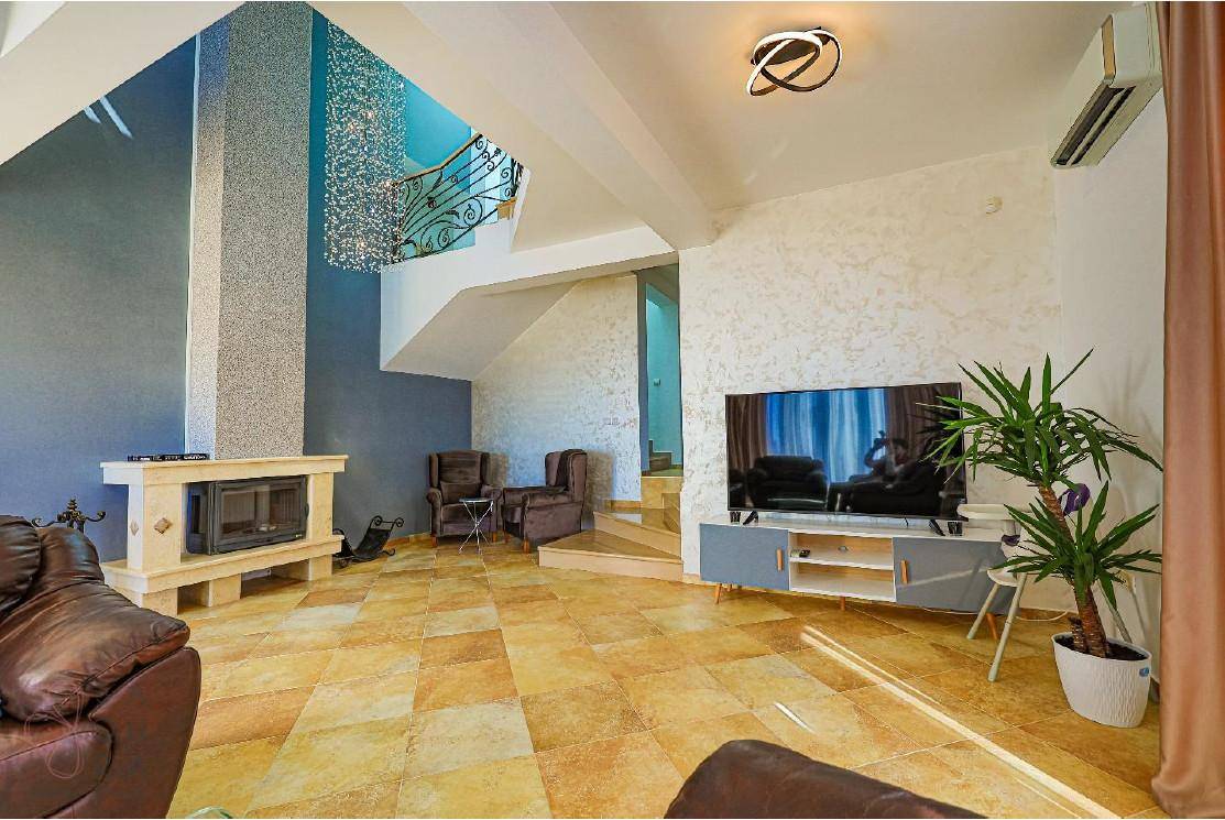 Elegantes Wohnzimmer mit Kamin, Ledersofas und einem Fernseher, akzentuiert durch eine Klimaanlage.