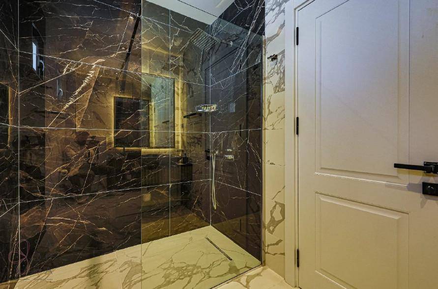 Elegante Dusche mit dunklen Marmorfliesen und Glasabtrennung im modernen Badezimmer.