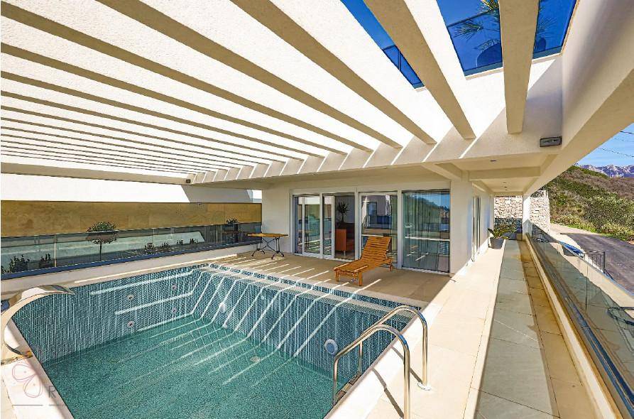 Großer Poolbereich mit Pergola, Liegestuhl und Zugang zu den Innenräumen.