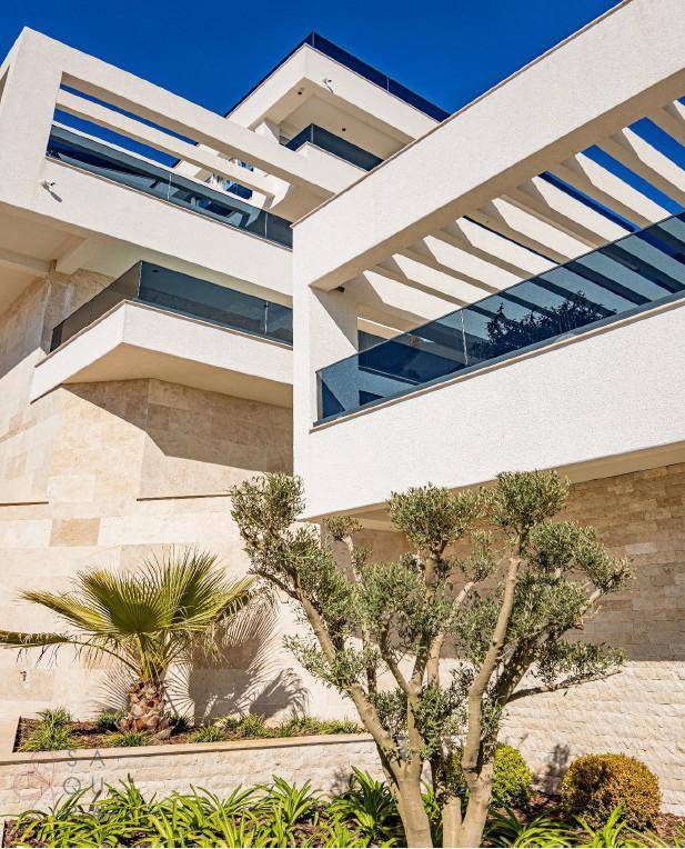 Moderne Architektur mit weißen Fassaden, Balkonen und dekorativen Pflanzen im Vordergrund.