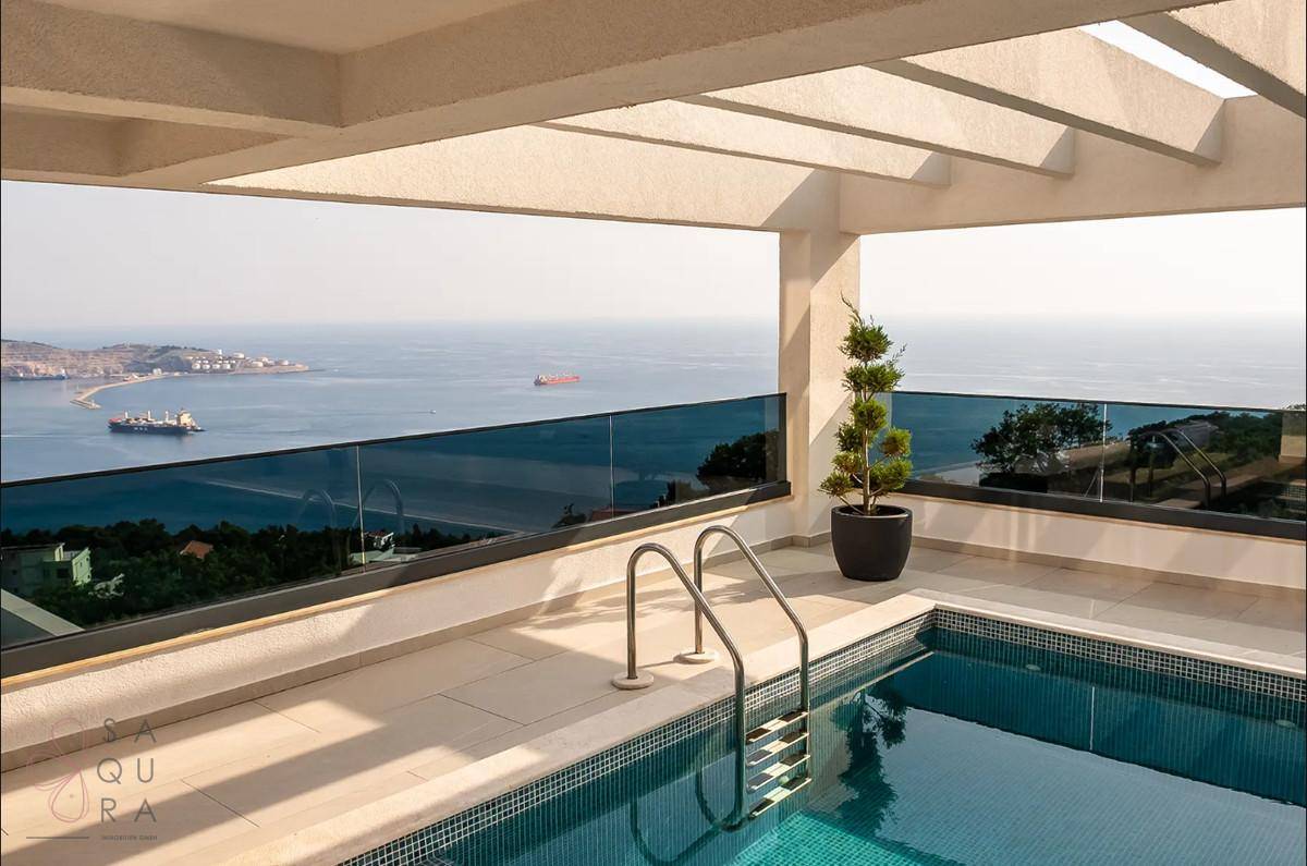 Infinity-Pool mit Meerblick und Glasgeländer, ideal für entspannte Stunden im Freien.