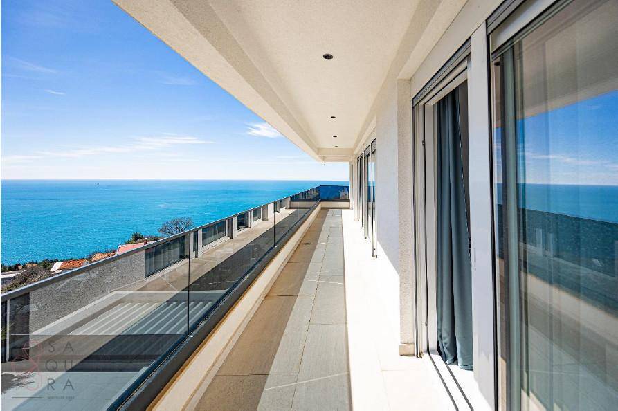 Langer Balkon mit Glasgeländer und unverbautem Blick auf das weite, blaue Meer.
