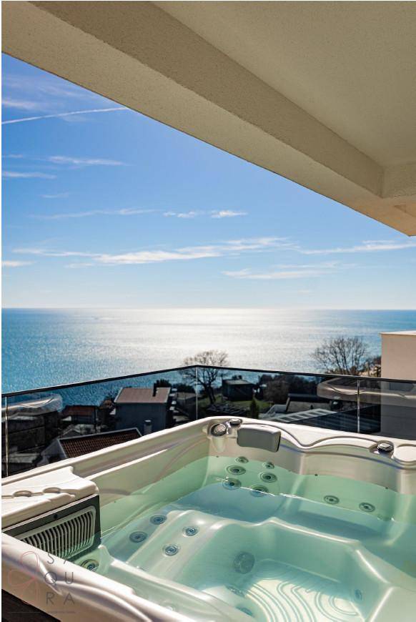 Whirlpool auf der Terrasse mit atemberaubendem Meerblick unter blauem Himmel.