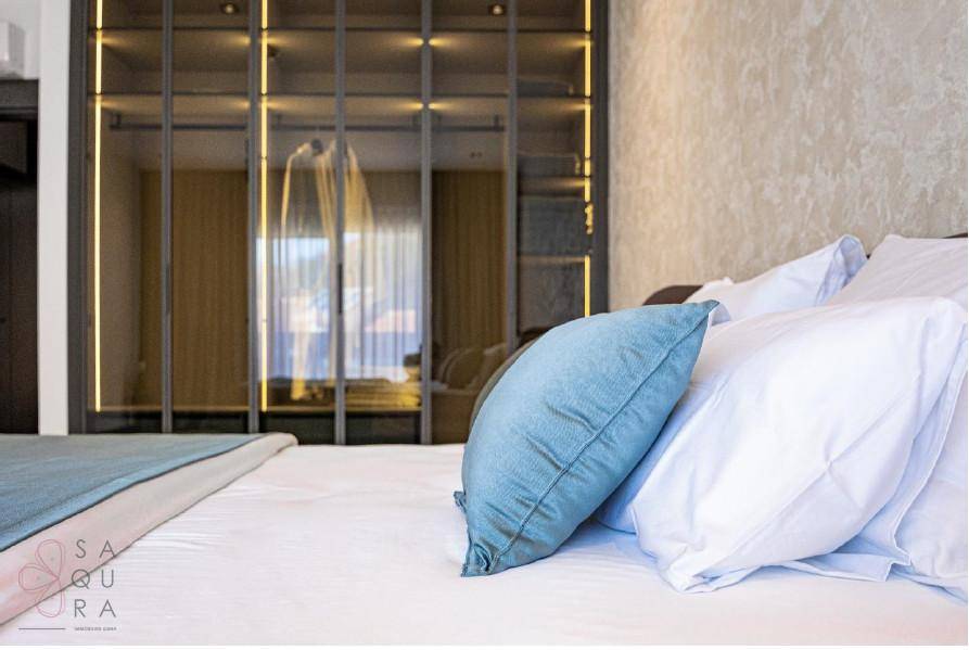 Schlafzimmer mit großem Bett, reflektierenden Schranktüren und blauen Kissen für Komfort.
