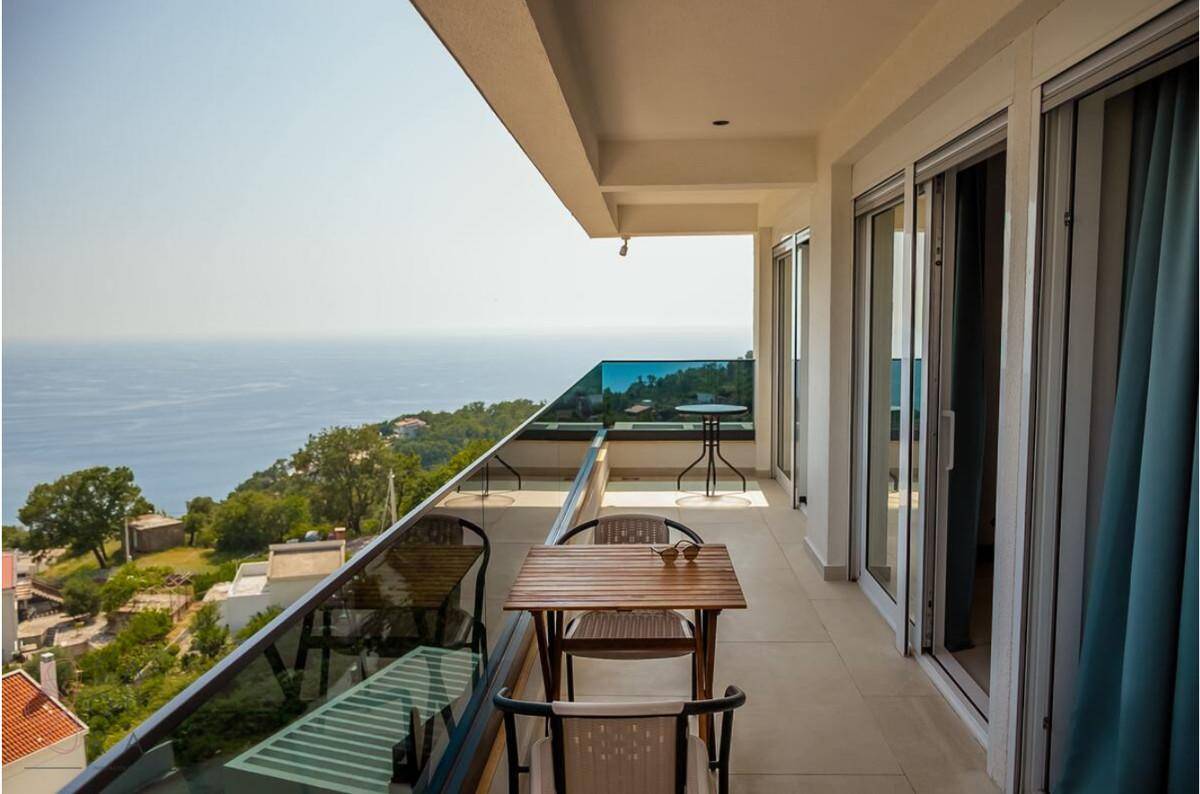Geräumiger Balkon mit Meerblick, Esstisch und Glasgeländer für ungestörte Aussicht.
