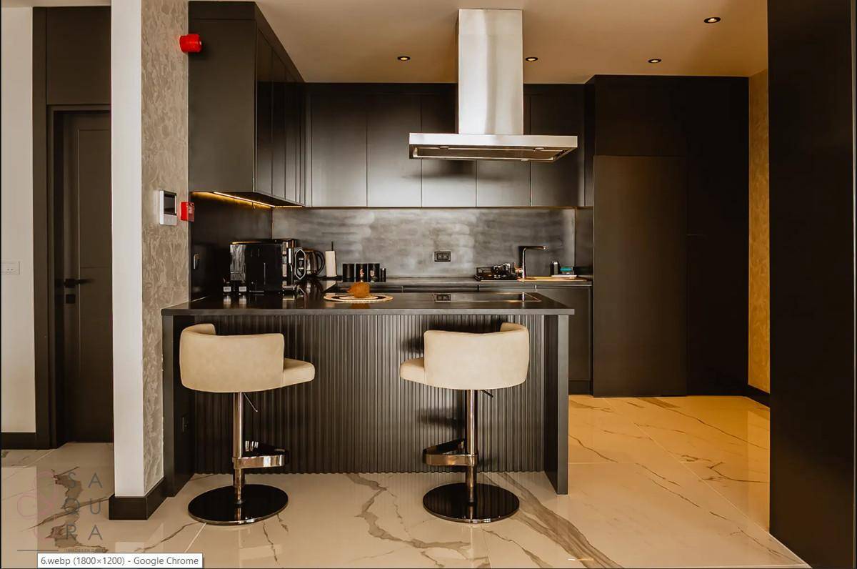 Moderne Küche mit Frühstücksbar, Barhockern und hochwertigen Geräten in dunklem Design.