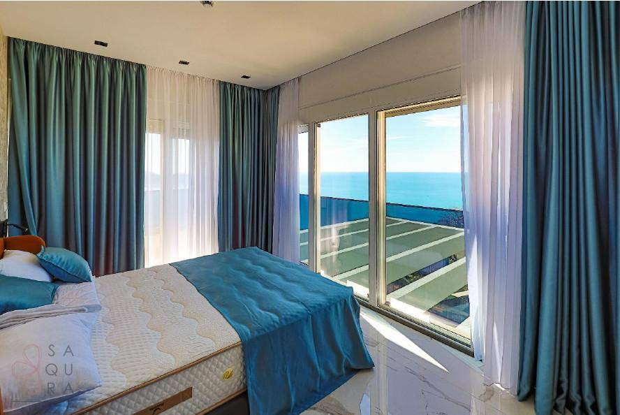 Schlafzimmer mit Panoramablick auf das Meer, großen Fenstern und einem hellen, modernen Ambiente.