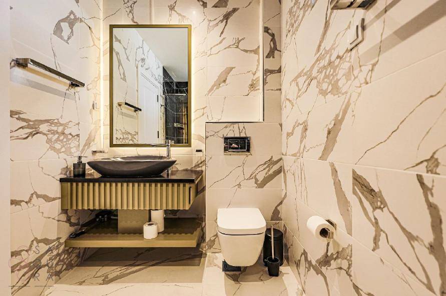 Luxuriöses Badezimmer mit Marmorfliesen, modernem Waschtisch und Wand-WC.