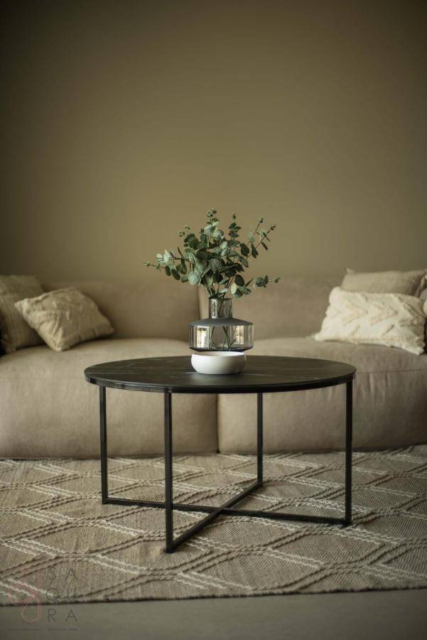 Gemütliches Wohnzimmer mit beigem Sofa, rundem Couchtisch und dekorativer Pflanze.