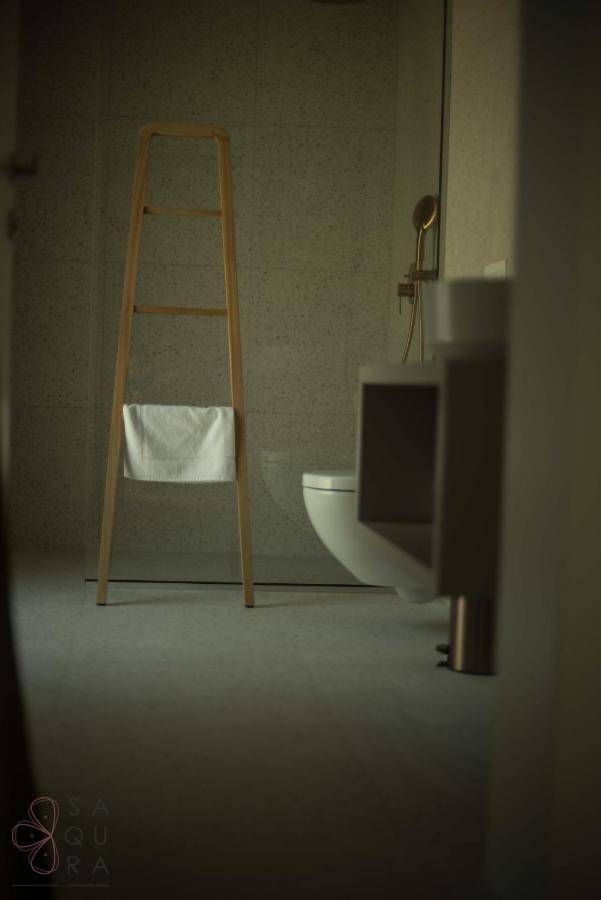 Minimalistisches Badezimmer mit Holztuchleiter und wandhängender Toilette, sehr modern.