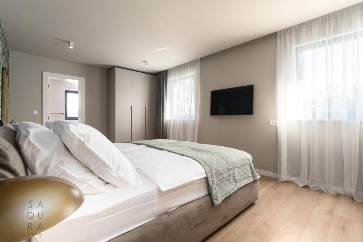 Helles Schlafzimmer mit großem Bett, Kleiderschrank und hellem Holzboden.
