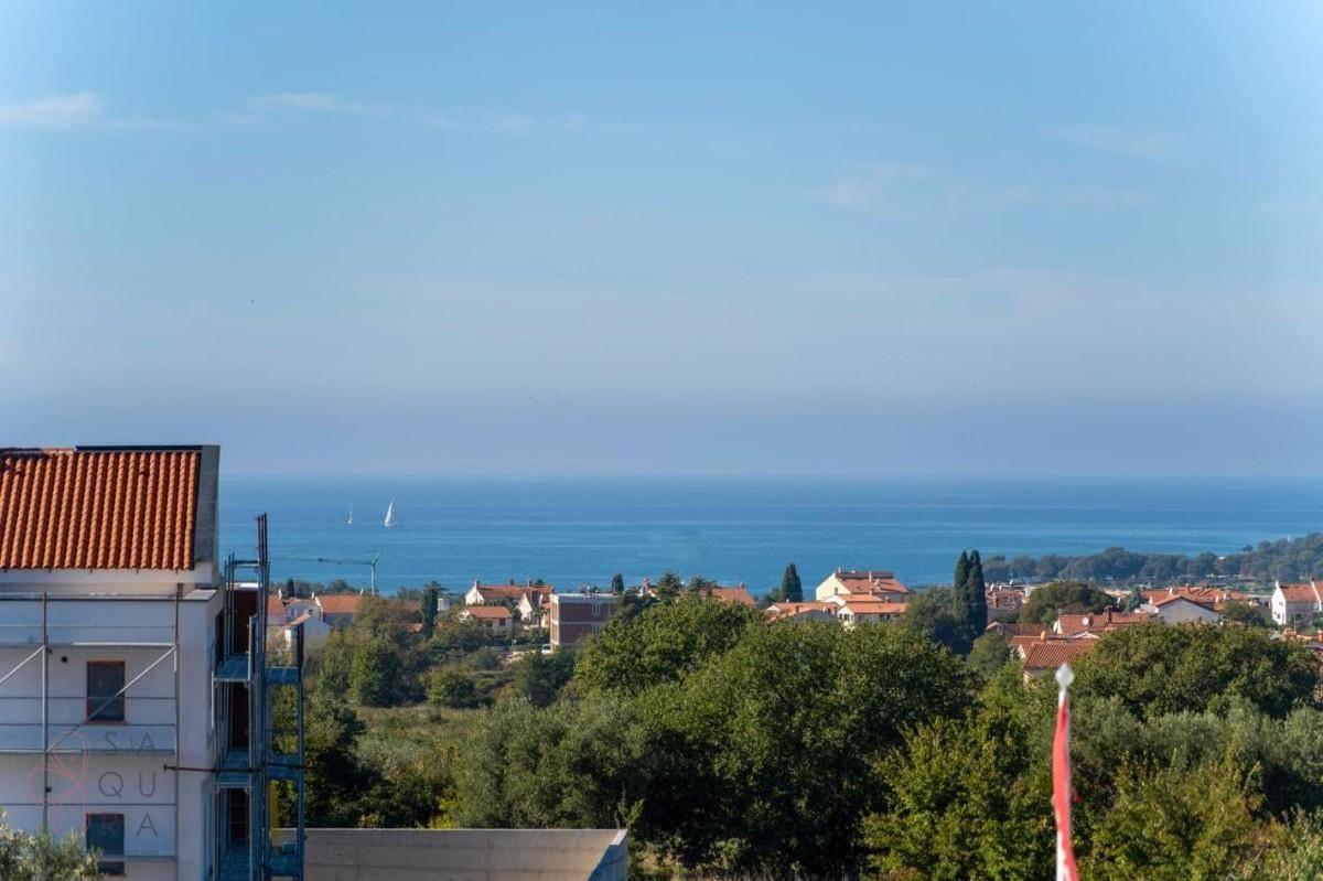Weitblick auf das blaue Meer und die Küstenlandschaft, mit einem Gebäude im Vordergrund.