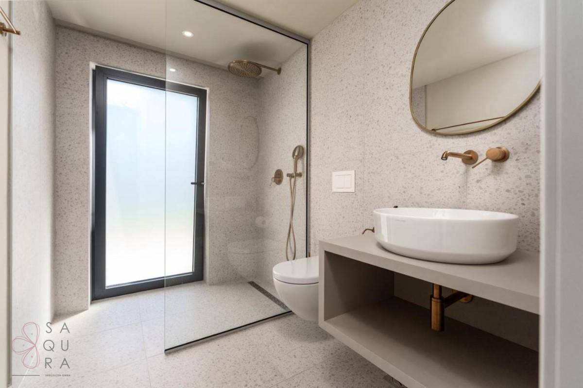Modernes Badezimmer mit begehbarer Dusche, wandhängendem WC und elegantem Waschbecken.