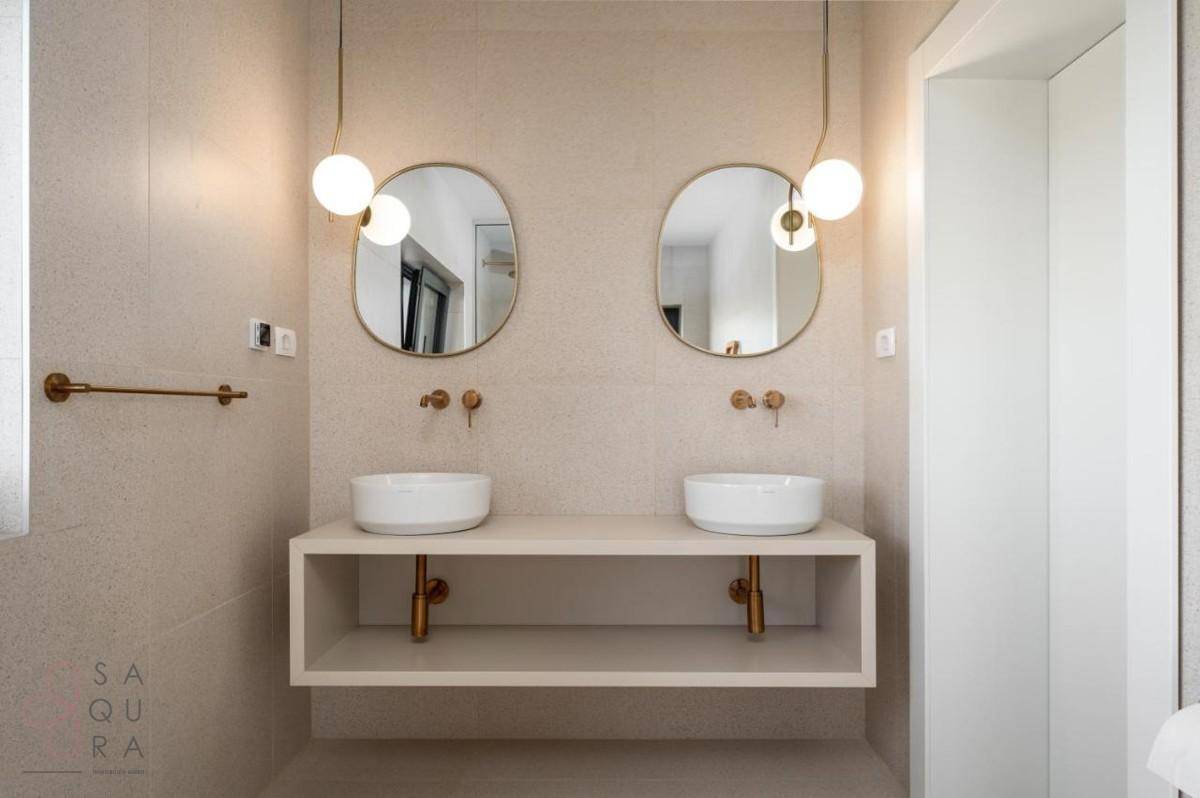 Stilvolles Badezimmer mit Doppelwaschbecken, zwei Spiegeln und modernen Leuchten.
