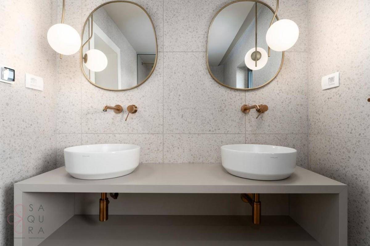 Detailansicht des Doppelwaschbeckens mit modernen Armaturen und ovalen Spiegeln im Badezimmer.