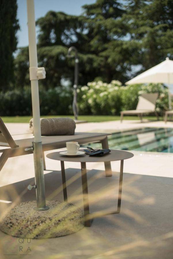 Beistelltisch mit Kaffeetasse und Handy am Poolbereich mit Liegestühlen im Hintergrund.