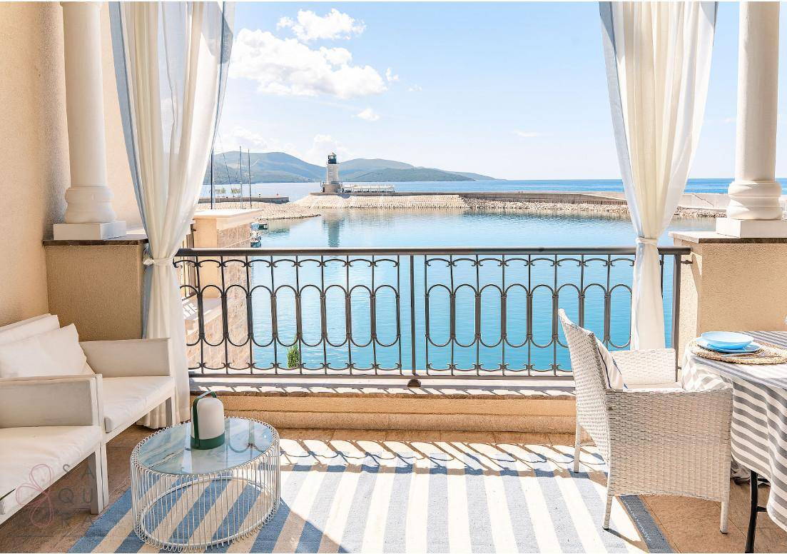 Möblierter Balkon mit Säulen und einem malerischen Blick auf das Meer und den Leuchtturm.