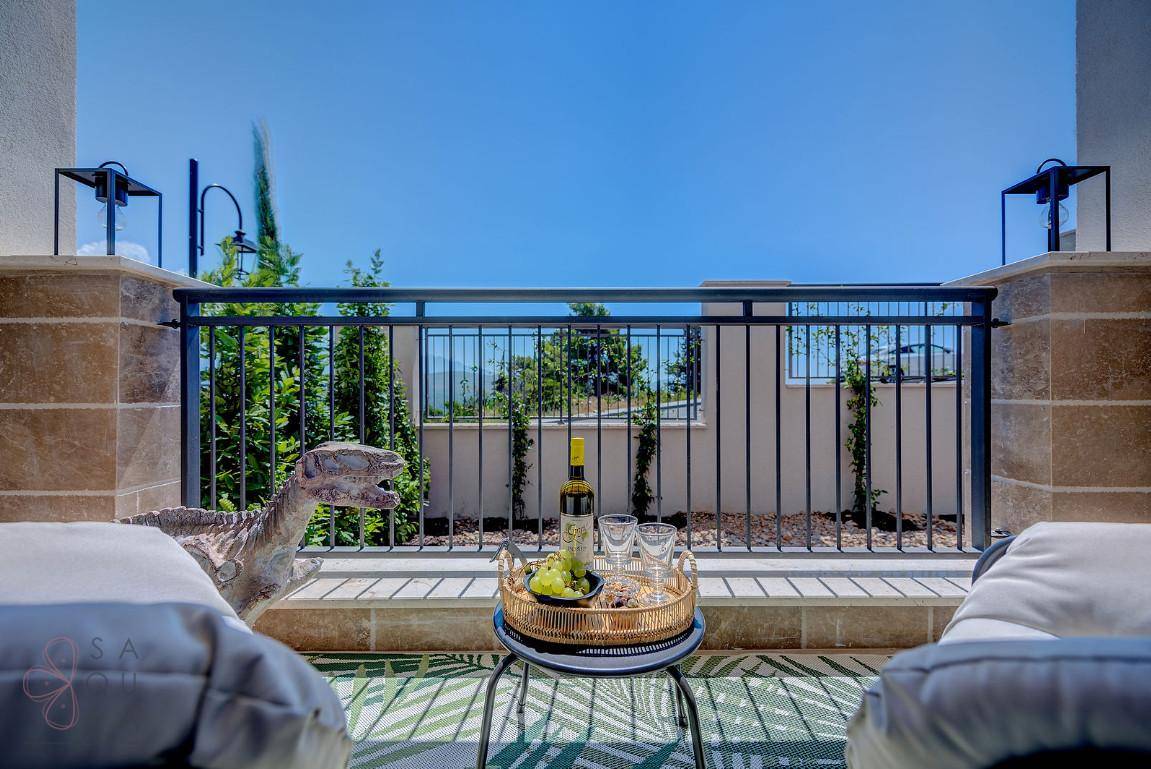Ein gemütlicher Balkon mit Sitzgelegenheiten, Wein und Obst, bietet einen weiten Blick.