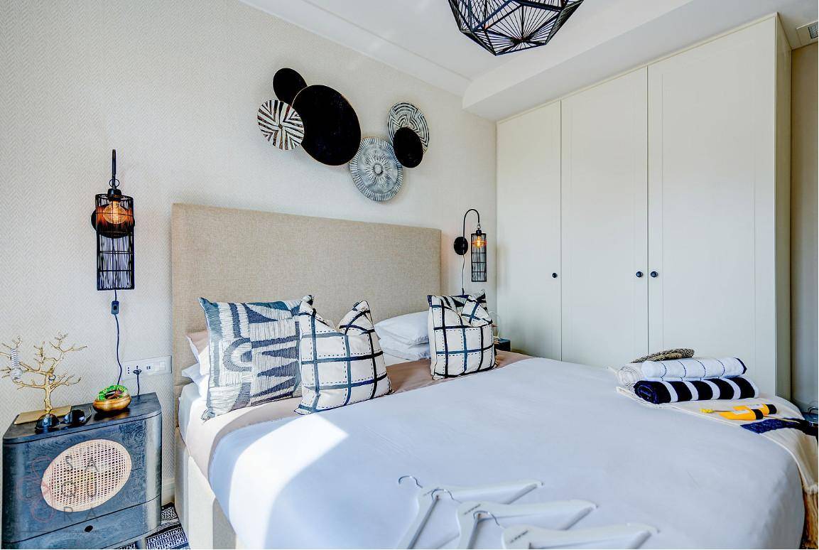 Helles Schlafzimmer mit modernen Möbeln, Einbauschränken und dekorativen Wandelementen.