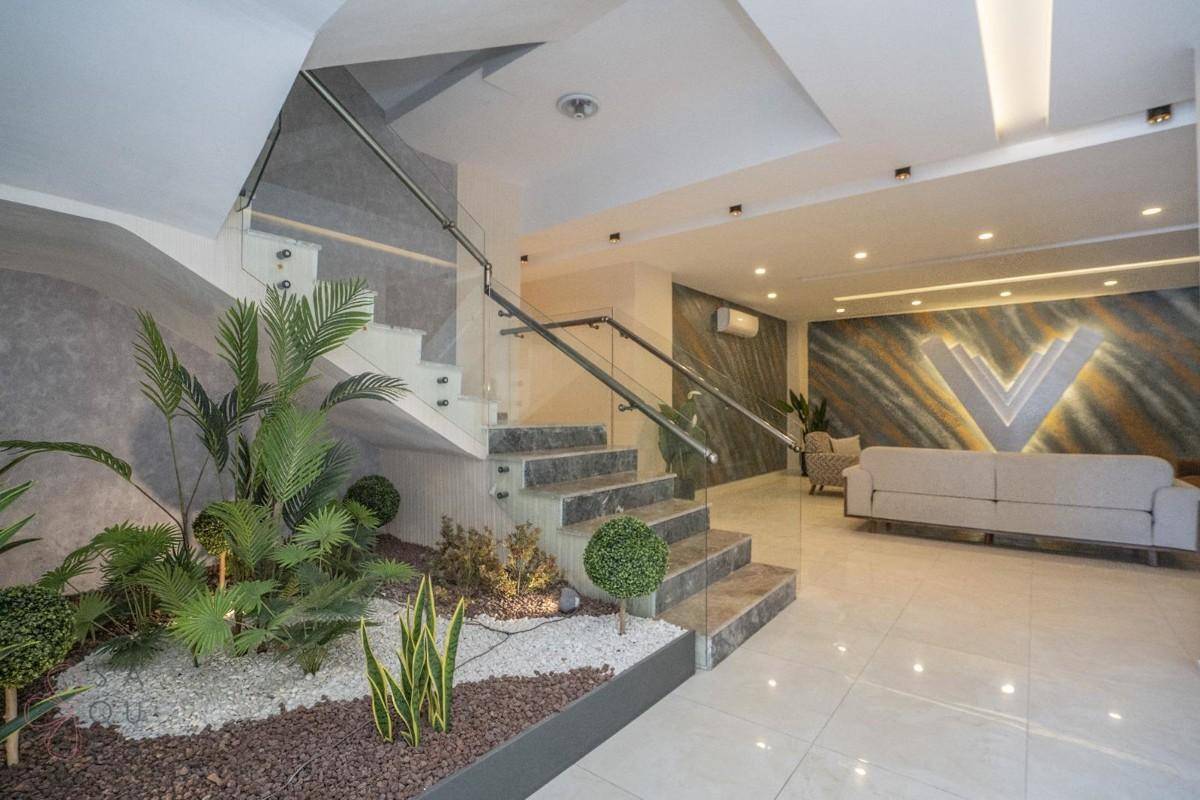 Elegante Lobby mit moderner Treppe, Pflanzen und bequemen Sitzgelegenheiten, die zum Verweilen einladen.