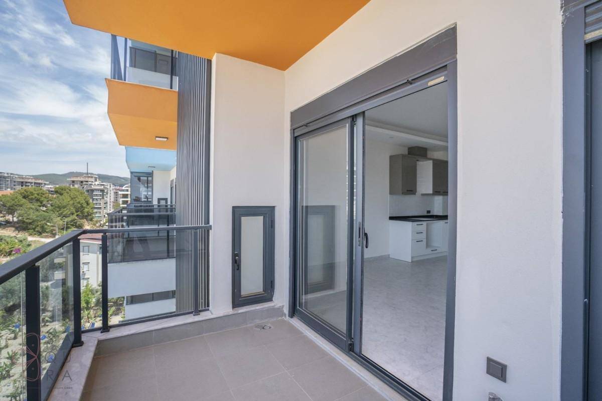 Heller Balkon mit Schiebetür und Blick auf die Umgebung sowie in die offene Küche.