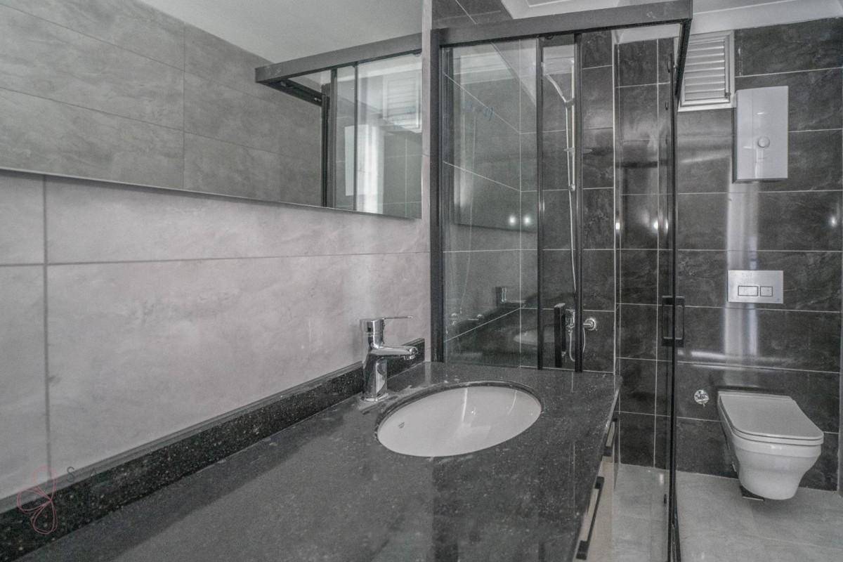 Modernes Badezimmer mit dunklen Fliesen, Einzelwaschbecken und begehbarer Dusche, elegant gestaltet.