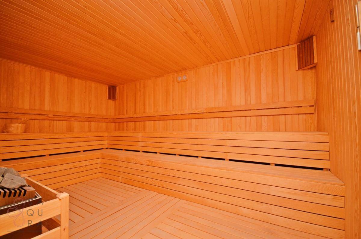 Geräumige Holzsauna mit mehreren Bänken und traditionellem Saunaofen für tiefe Entspannung.