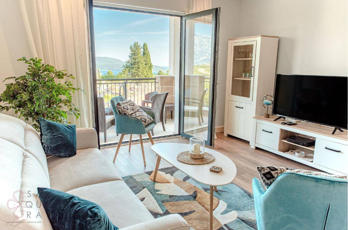 Lichtdurchflutetes Wohnzimmer mit Balkon und Panoramablick auf das Meer und die Küste.