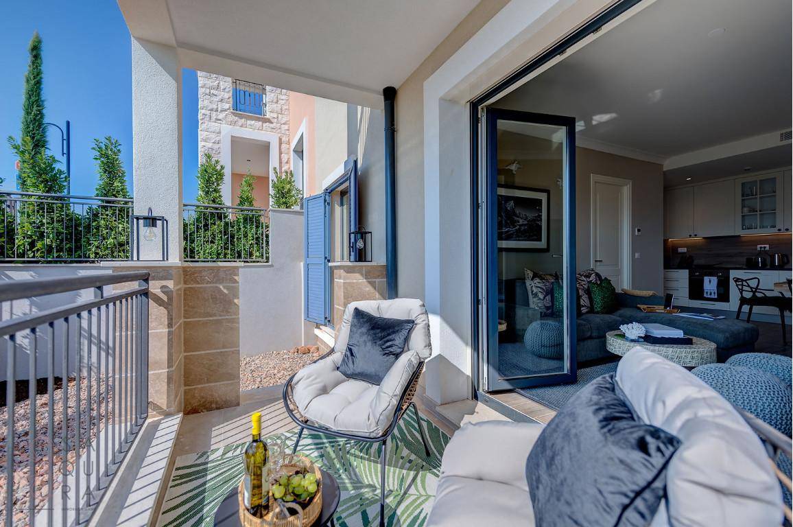 Gemütlicher Balkon mit Sitzgelegenheiten und Blick in den offenen Wohn- und Küchenbereich.