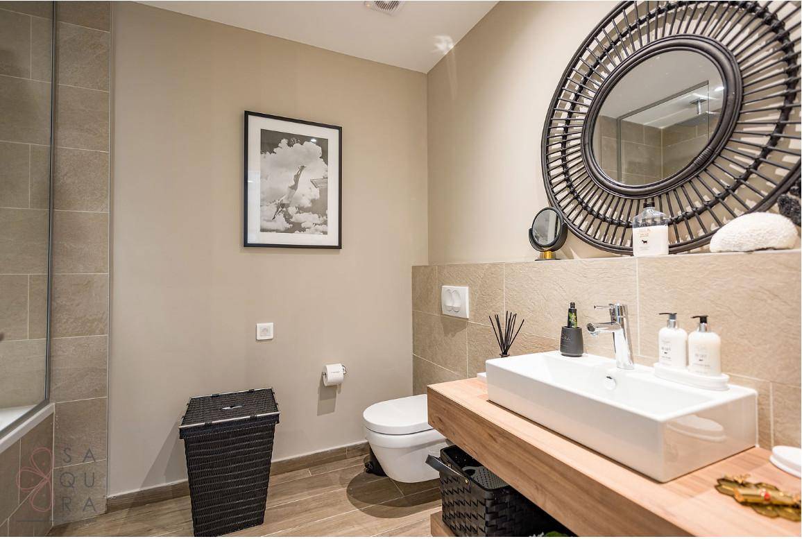 Stilvolles Badezimmer mit modernem Waschtisch, WC und einem großen runden Wandspiegel.