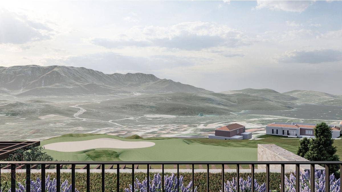 Panoramablick von einem Balkon auf einen Golfplatz, umgeben von Bergen und einer weiten Landschaft.