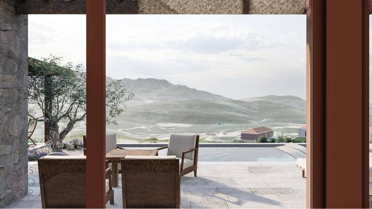 Heller Innenraum mit großen Glasfronten, die den Blick auf den Pool und die Berglandschaft freigeben.