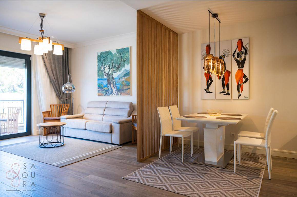 Heller Wohn- und Essbereich mit Holztrennwand, modernem Esstisch und Zugang zum Balkon.