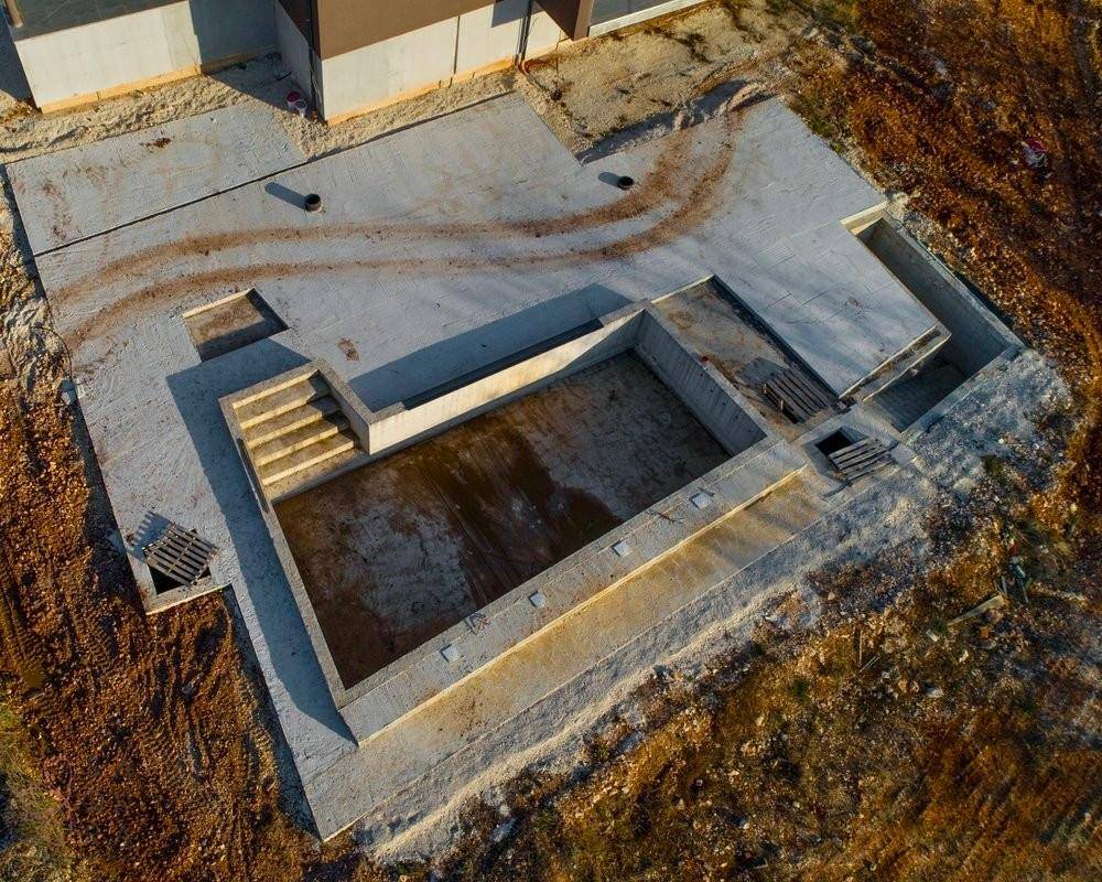 Rohbau des zukünftigen Pools mit Treppen und umliegender Betonfläche.