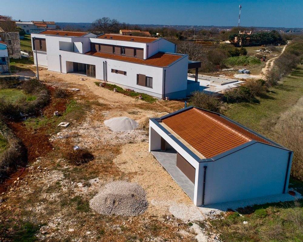 Luftaufnahme der modernen Villa und eines Nebengebäudes mit Ziegeldächern in ländlicher Umgebung.