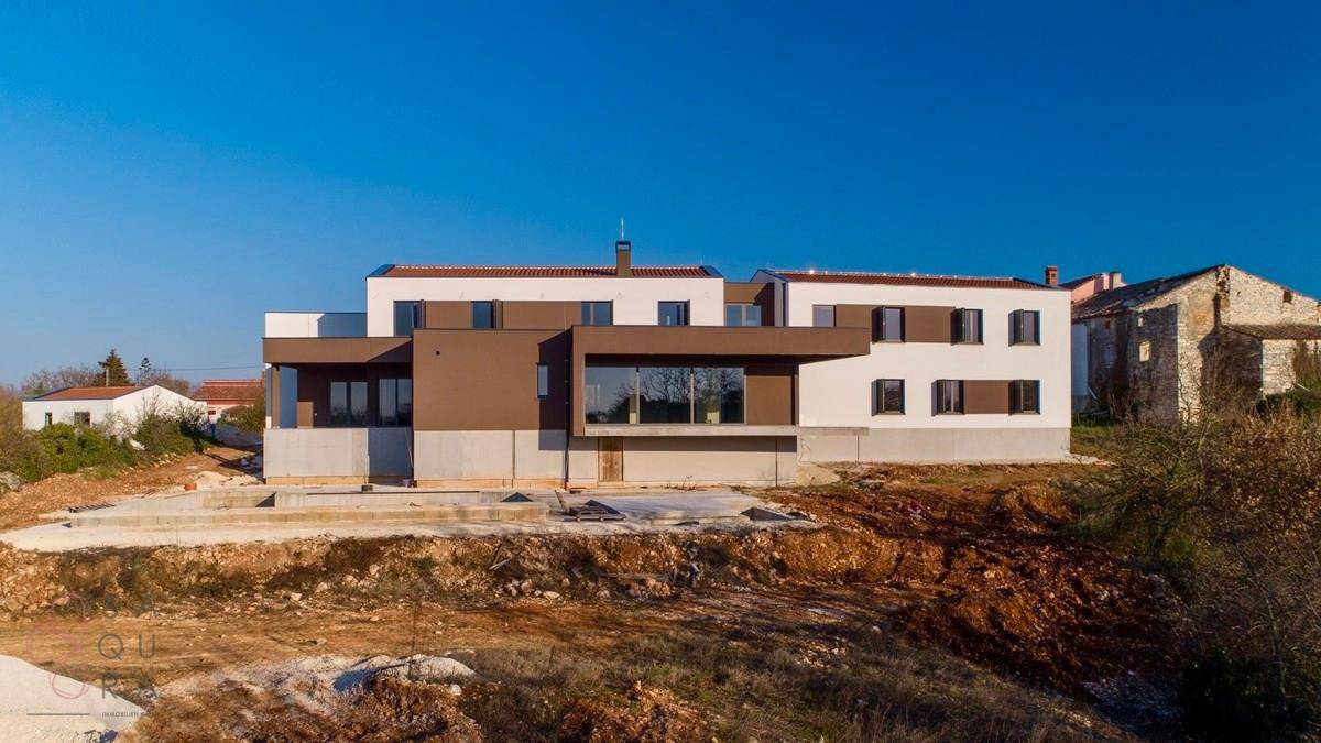 Gesamtansicht der modernen Villa mit unfertigem Poolbereich und ländlicher Umgebung.