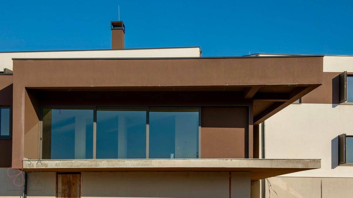Detailansicht der modernen Fassade mit großen Glasfronten und braunen Akzenten.