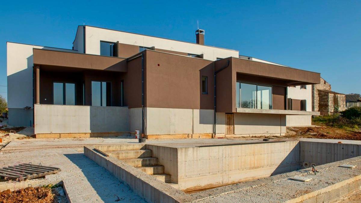Ansicht der modernen Villa mit unfertigem Poolbereich unter klarem Himmel.