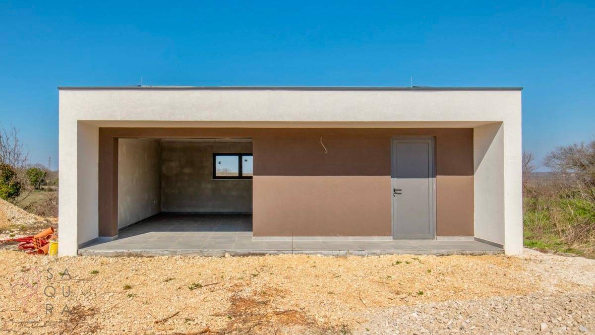 Modernes Nebengebäude, vermutlich eine Garage, mit offener Front und Seitentür.