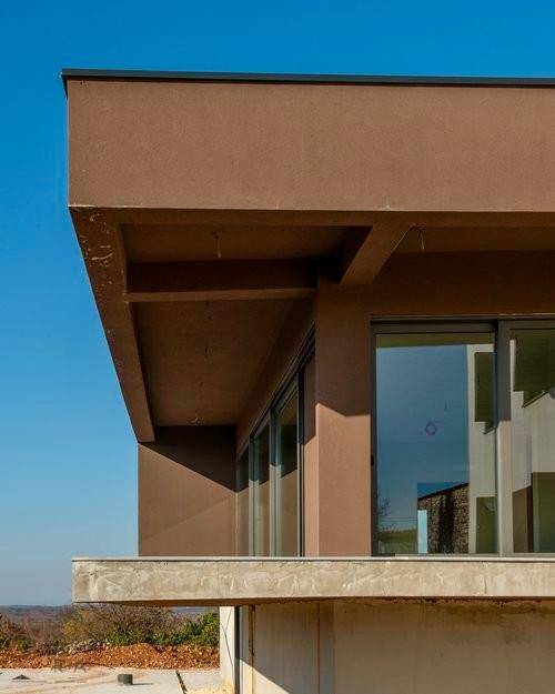 Architektonisches Detail eines auskragenden Gebäudeteils mit großen Glasfronten.