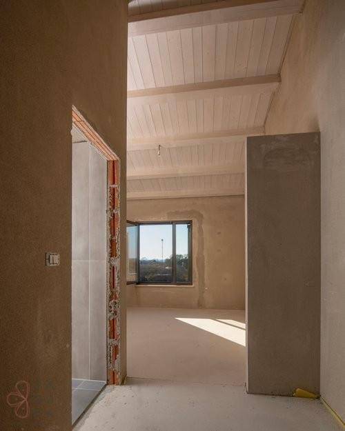Unfertiger Flur mit Blick in ein Zimmer mit Fenster und Dachschräge, viel Tageslicht.