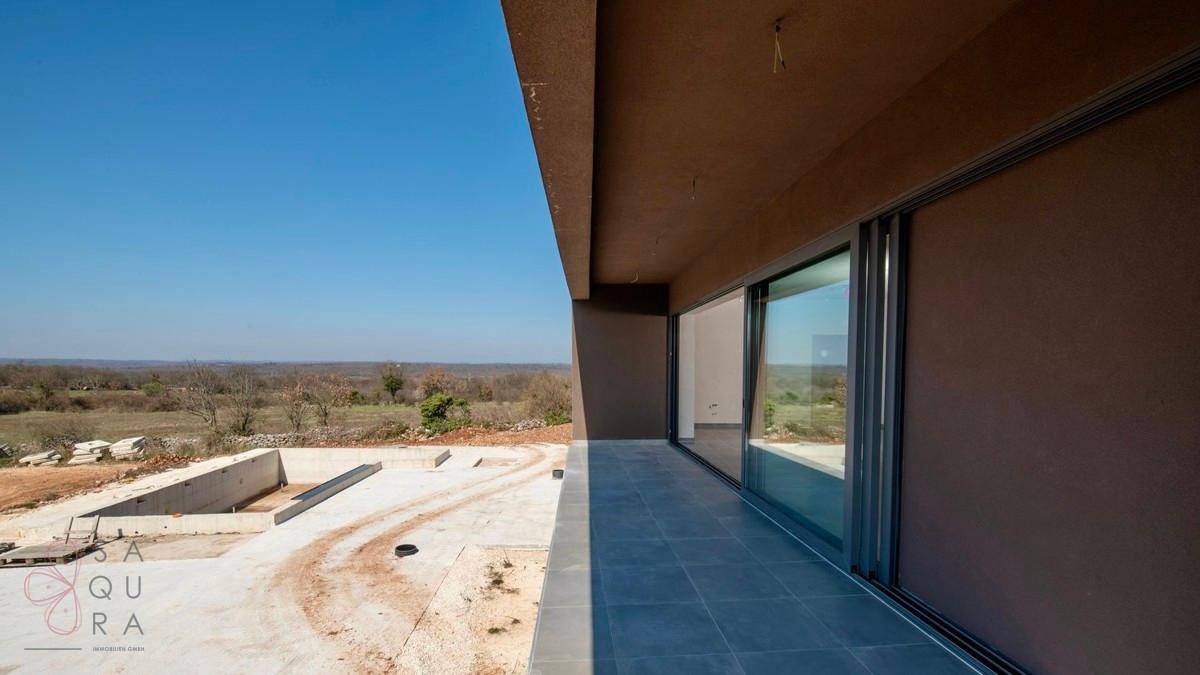 Große geflieste Terrasse im Rohbau mit weitem Blick über die unberührte Landschaft.