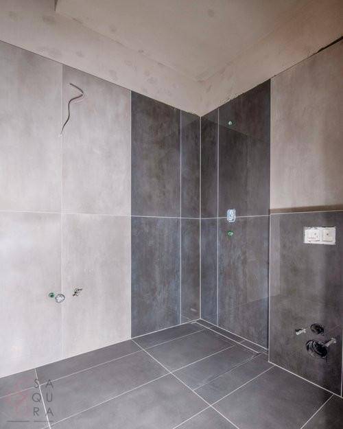Unfertiges Badezimmer mit modernen grauen und hellen Fliesen an Wänden und Boden.