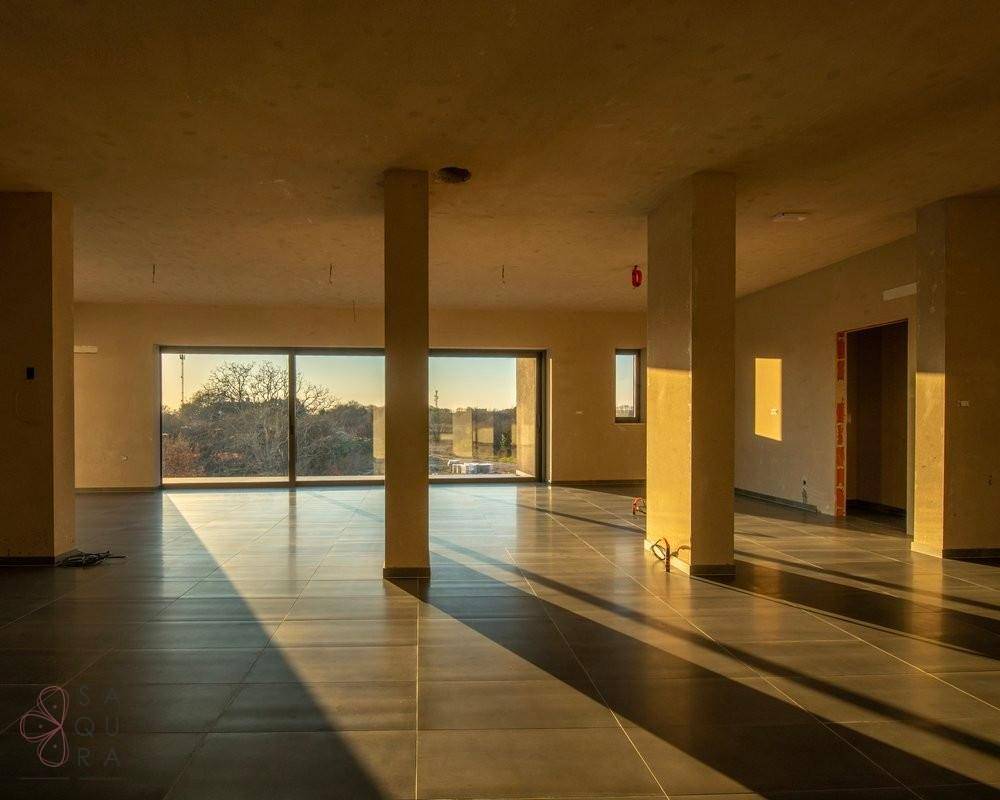 Großer, offener Wohnbereich im Rohbau mit vielen Fenstern und viel Tageslicht.