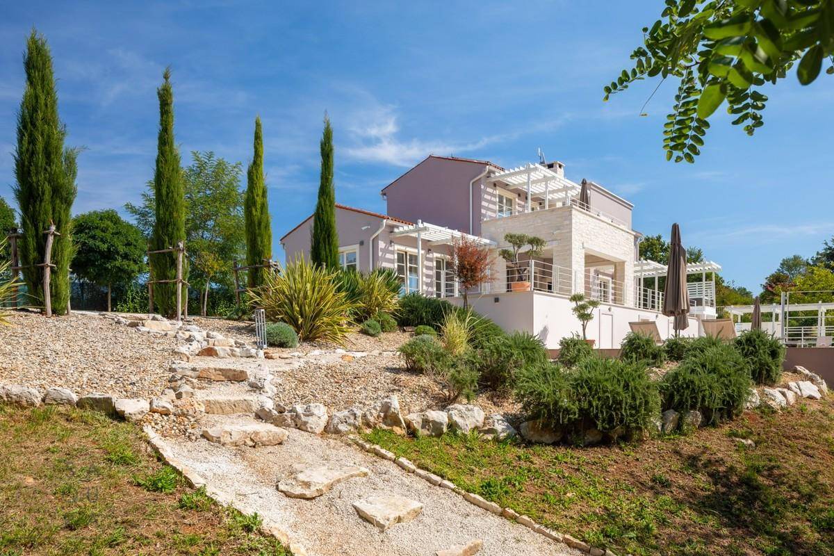 Mediterraner Gartenweg mit Steinstufen und üppiger Bepflanzung zur Villa führend.