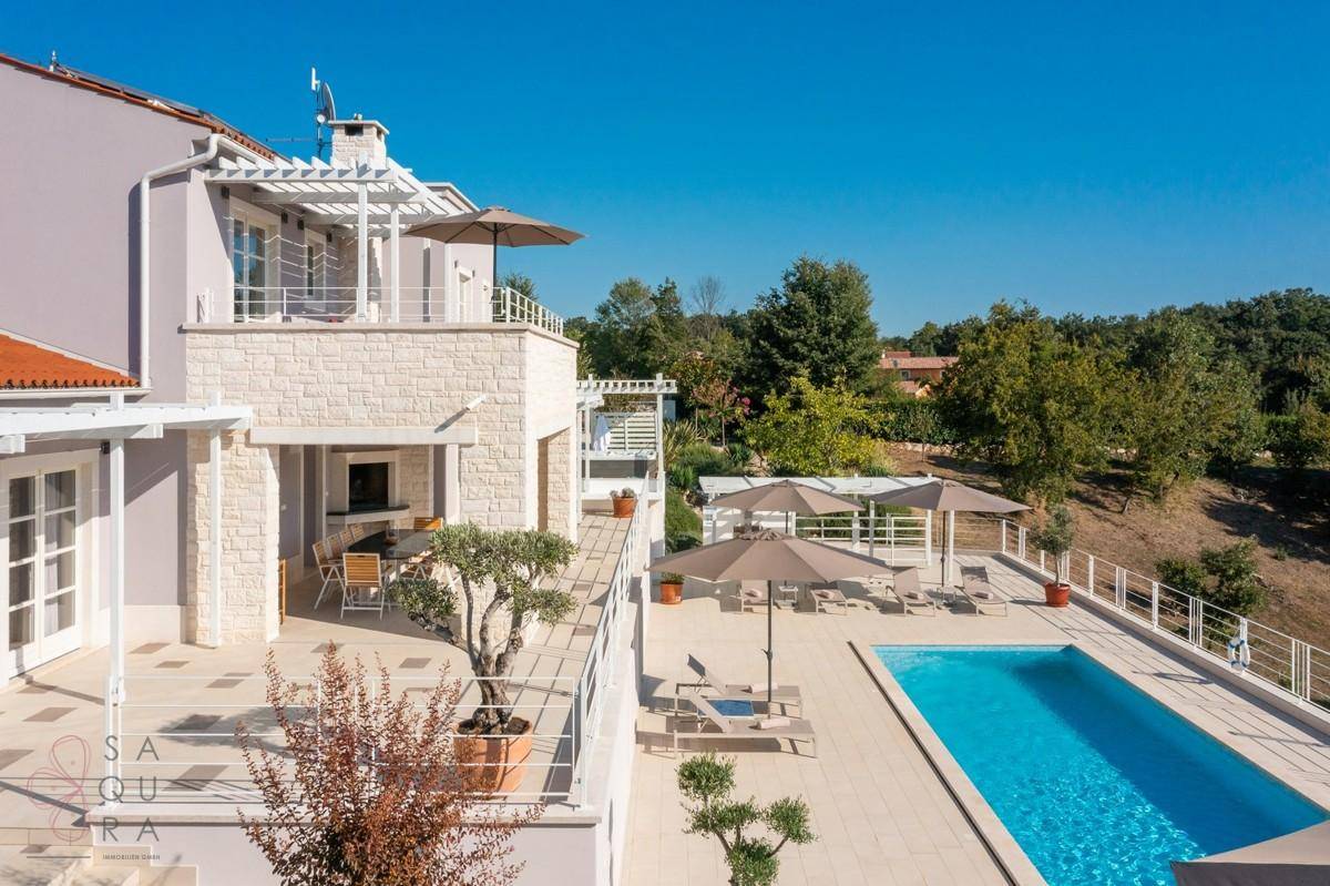 Weitläufige Poolterrasse mit Essbereich im Freien und Blick auf die grüne Umgebung.