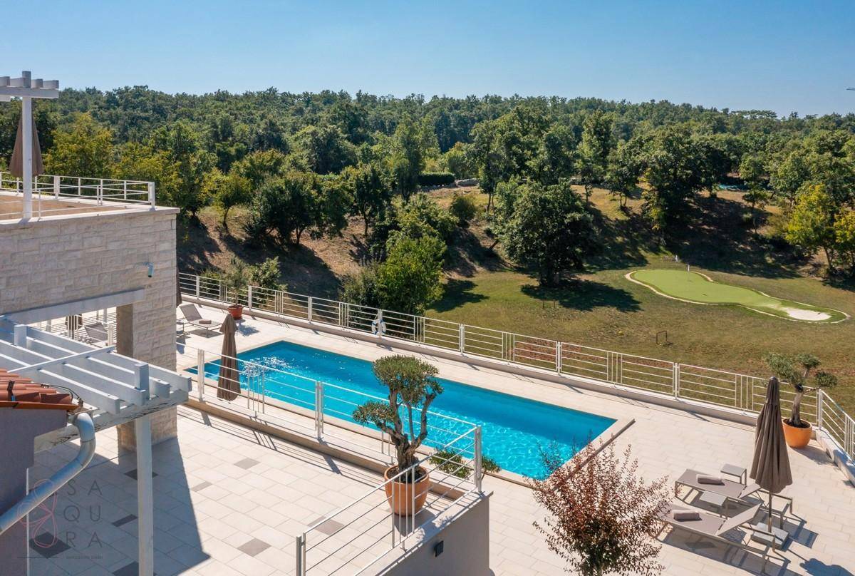 Poolbereich mit Liegestühlen und weitem Blick auf die umliegende Natur und Golfanlage.